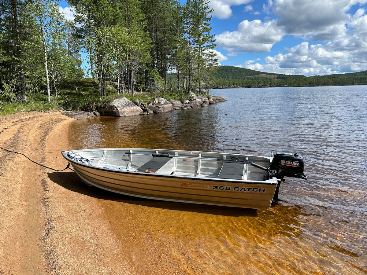 Aluminium boat with outboard motor by the shore.